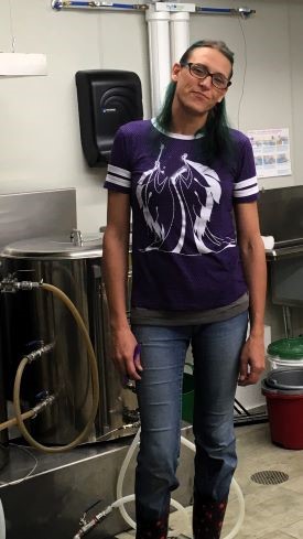 Female brewer standing in front of kettles.